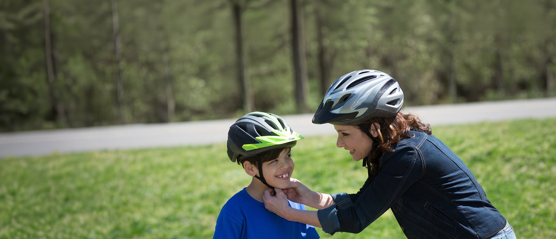 woman buckles bicycle helment on young son