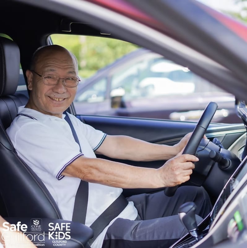 Senior man sits behind the wheel of a car