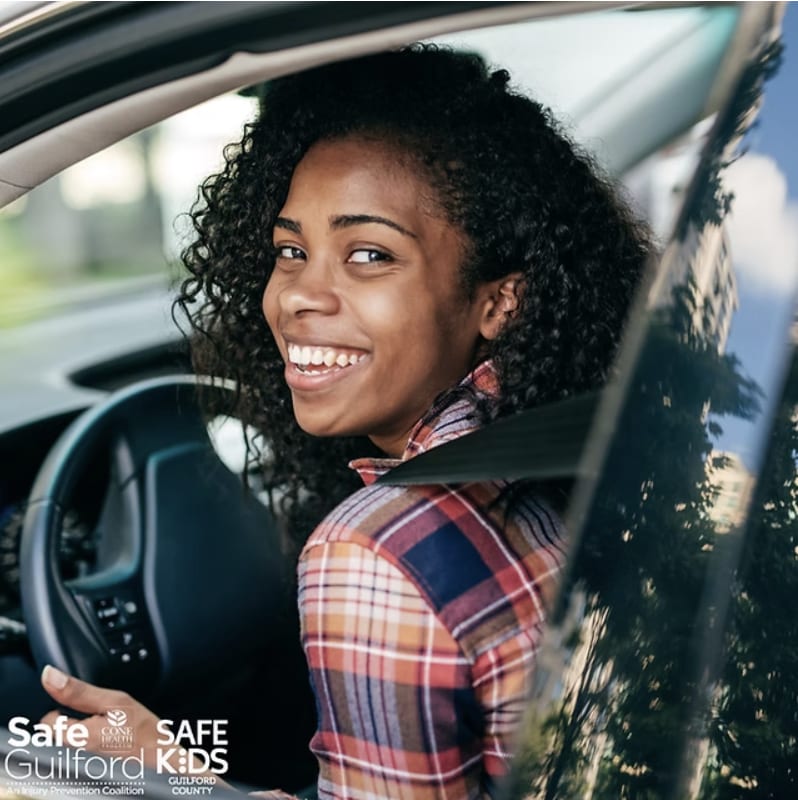Female teenager sites behind the wheel of a car